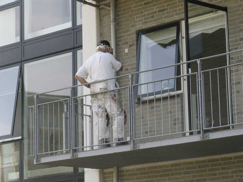 Een schilder aan het werk op een balkon